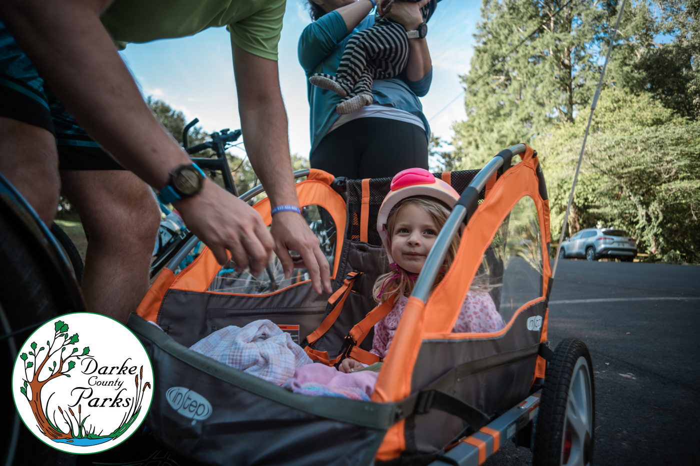 A father buckles his daughter into a bike carrier at Tour de Darke