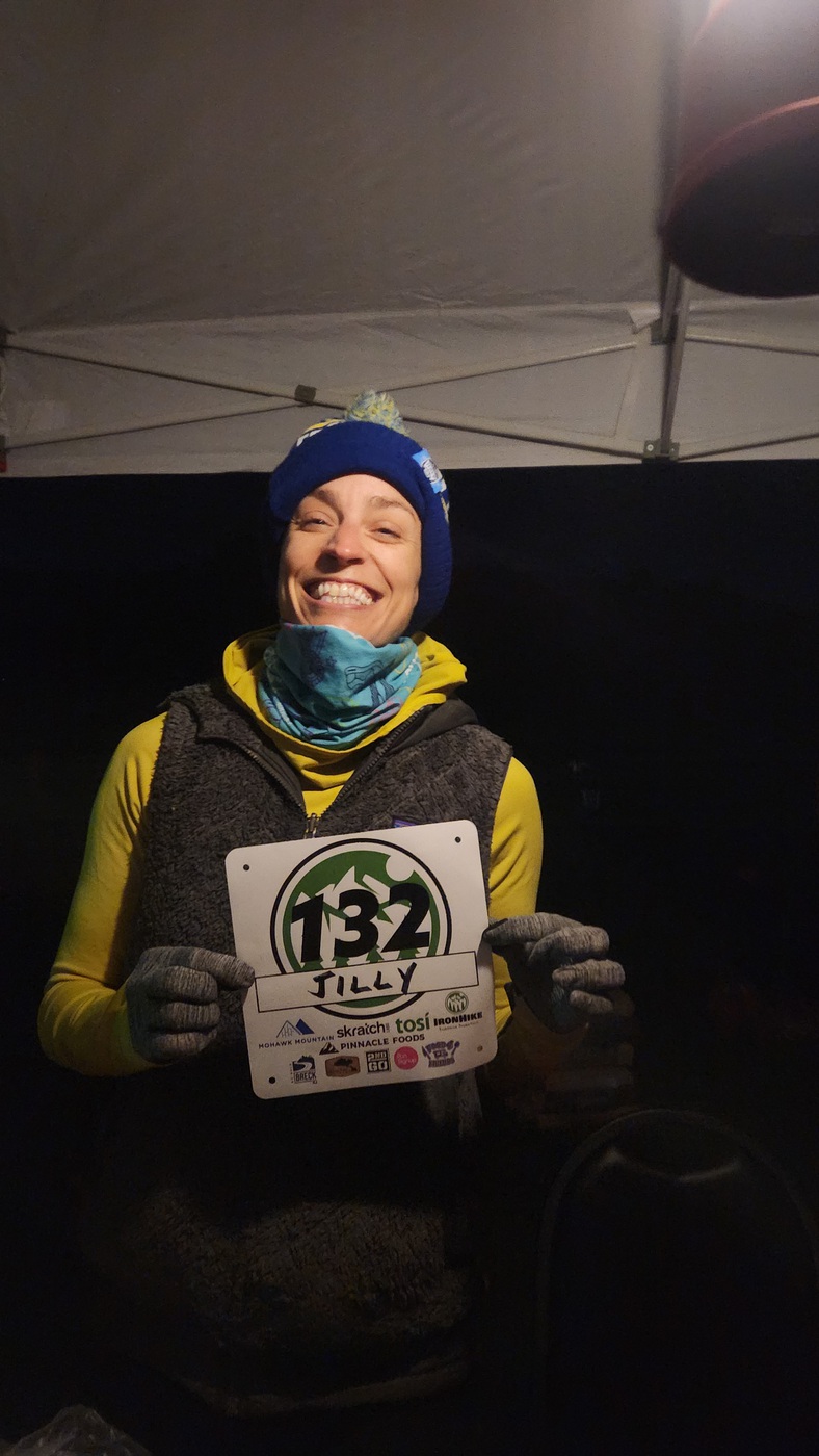 IronHike Mountain Athlete in a winter hat holding her bib at night, Mohawk Mountain Cornwall CT